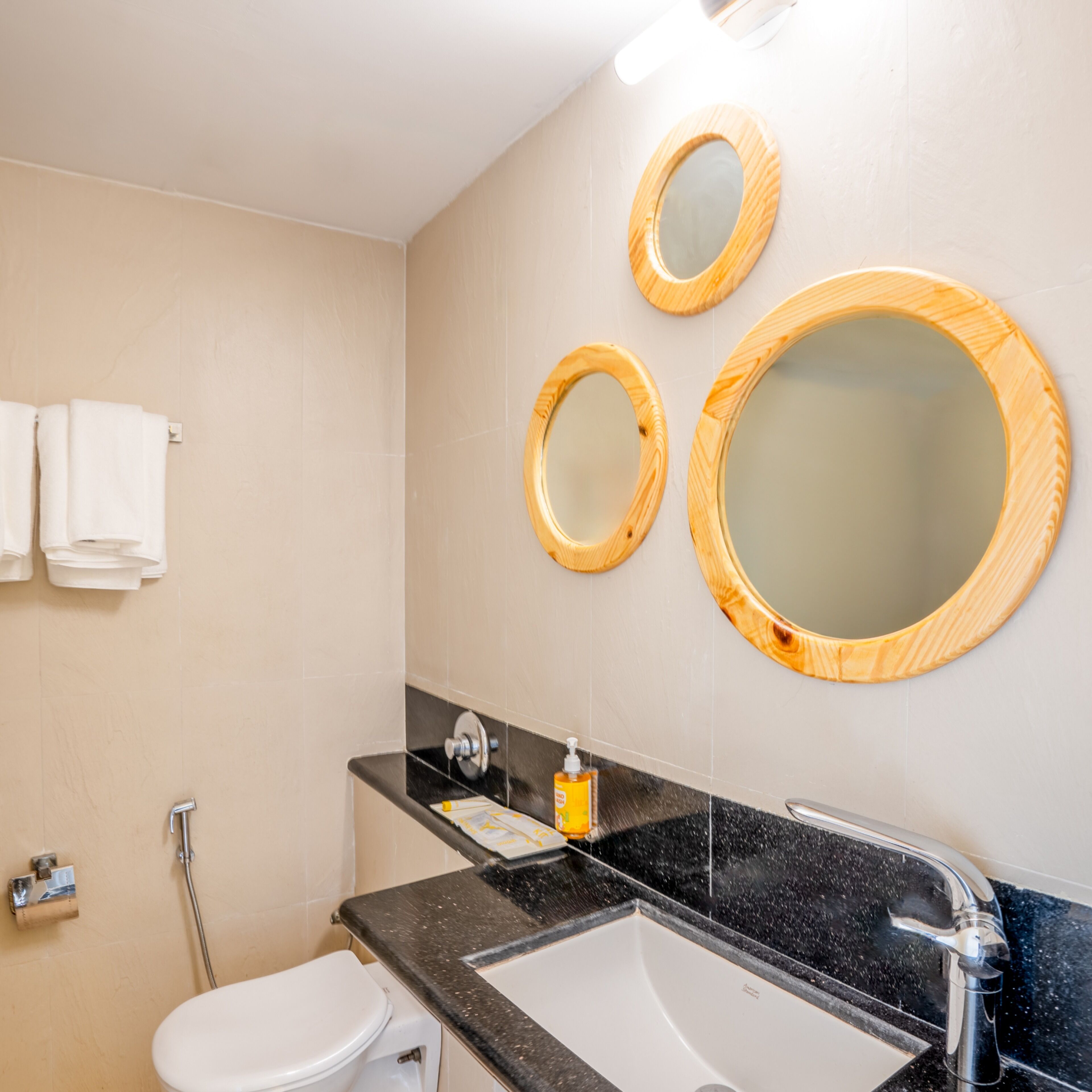 A bathroom with a toilet, sink, and three mirrors.