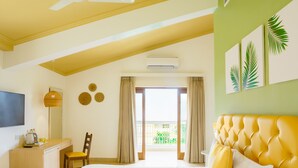 Una camera d'albergo con un letto, una scrivania, una sedia, un televisore e un balcone con tende.