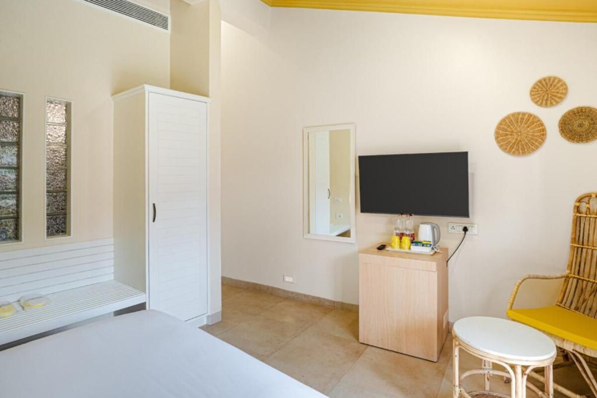 A bedroom with a bed, a wardrobe, a television, a small table, and a chair.