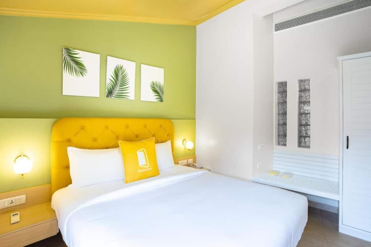 A hotel room with a bed, a nightstand, a wall-mounted lamp, and a window with a view.