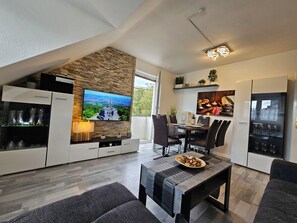 Eine moderne Küche mit Flachbildfernseher, Essbereich mit Stühlen und integriertem Weinkühlschrank.