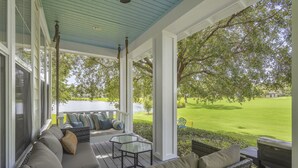 A covered porch with a seating area, a grill, and a view of a green lawn and trees. - Two Golf Carts ~ Golf Course Views ~ Pet Friendly (Miramar Beach)
