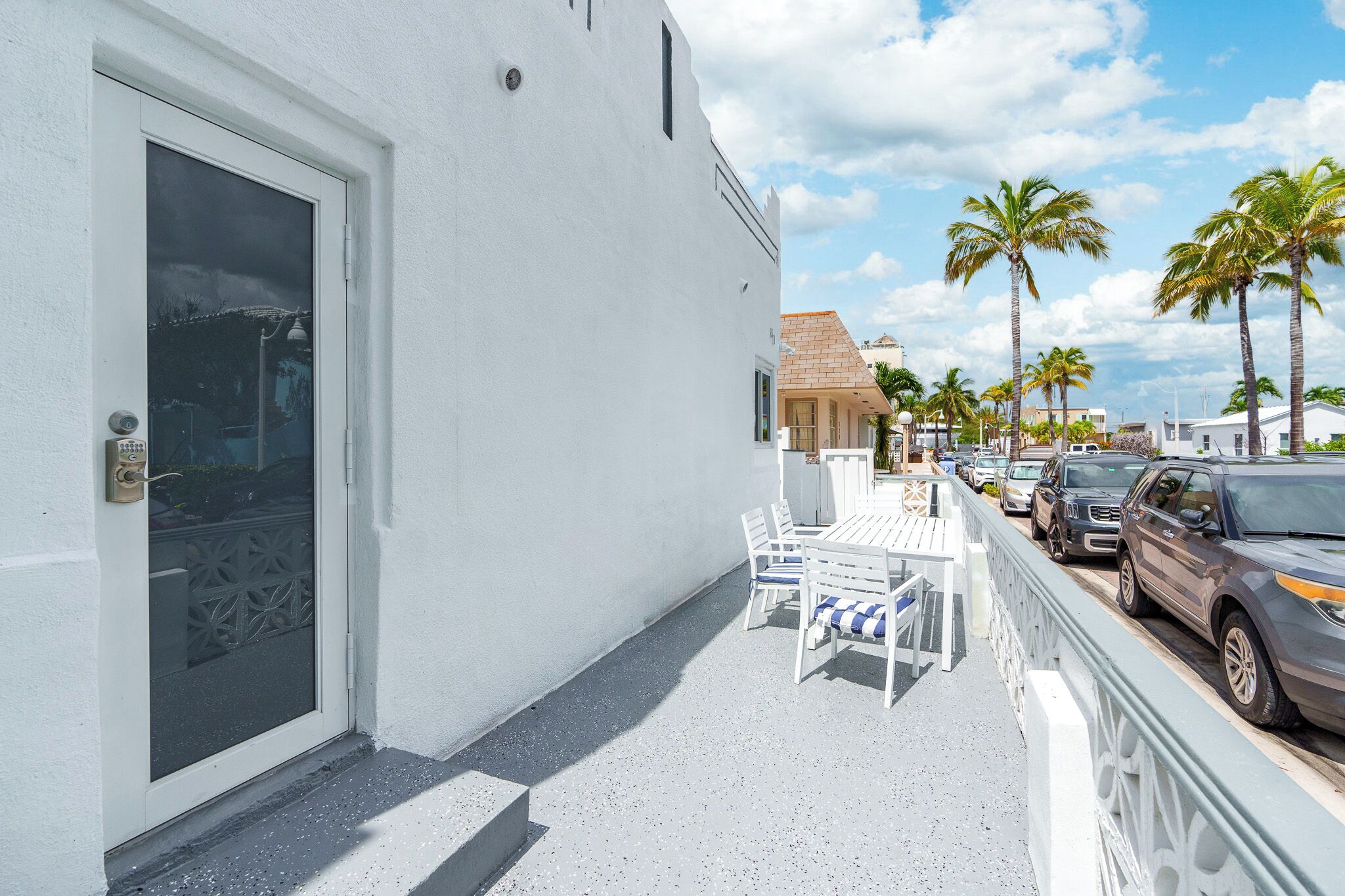 A white building with a door and a small patio area with a table and chairs.