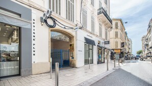 Una calle con locales comerciales, incluyendo una óptica y una agencia de alquiler de coches.