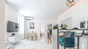Una cocina moderna con comedor, un sofá azul y un televisor montado en la pared.