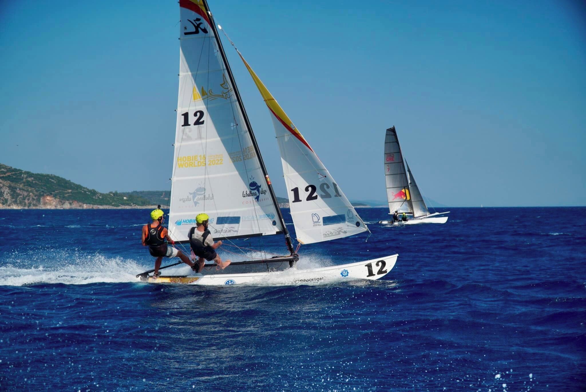 Two sailboats with the number 12 on their sails, sailing on the water.