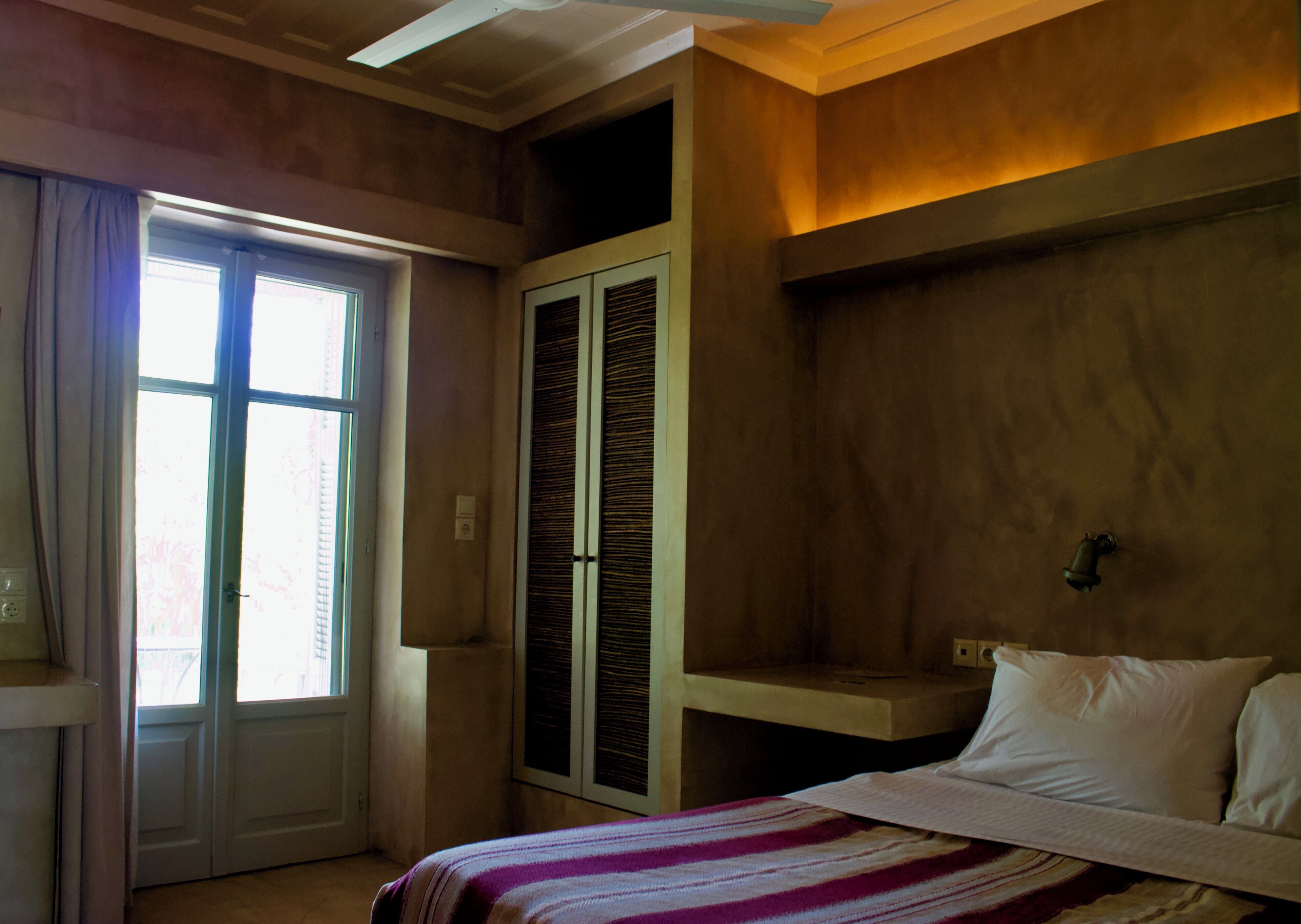 A bedroom with a bed, a window, a door, and a built-in wardrobe.