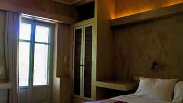 A bedroom with a bed, a window, a door, and a built-in wardrobe.