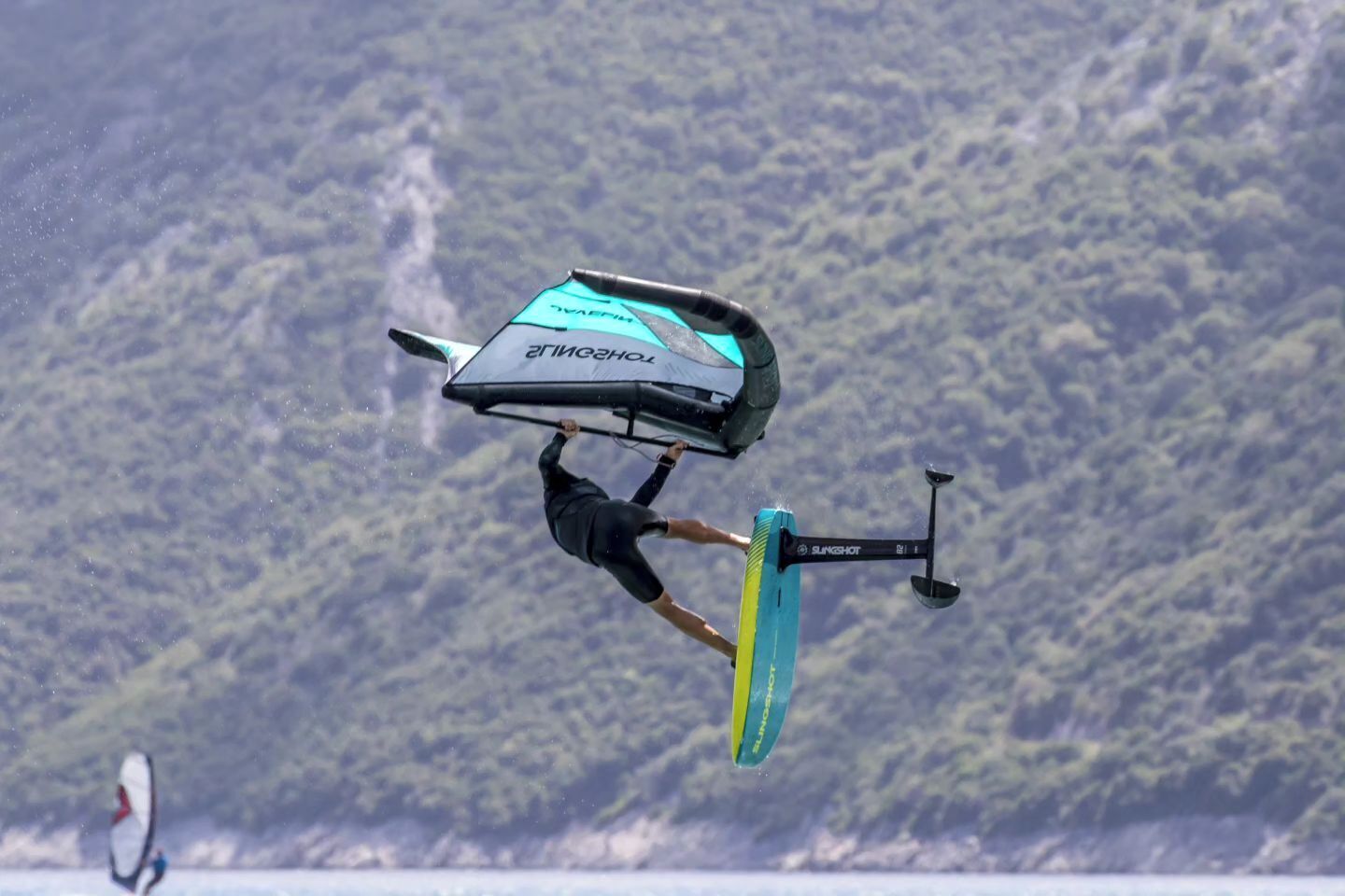 A person performing a trick on a wakeboard with a large board and a handle.