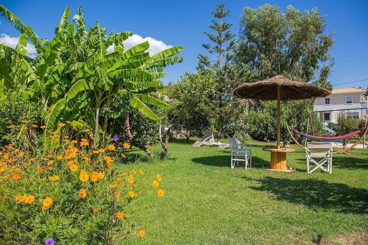 A garden with a hammock, chairs, and a thatched umbrella.