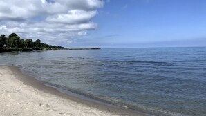 A beach with clear skies and calm waters. - Lakeside Resort Home: Sunsets, fishing, paddling - pet friendly (Avon Lake)