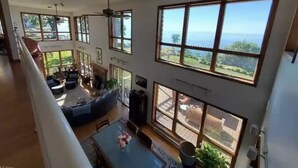 A spacious living area with large windows, a dining table, and a seating area. - Lakeside Resort Home: Sunsets, fishing, paddling - pet friendly (Avon Lake)