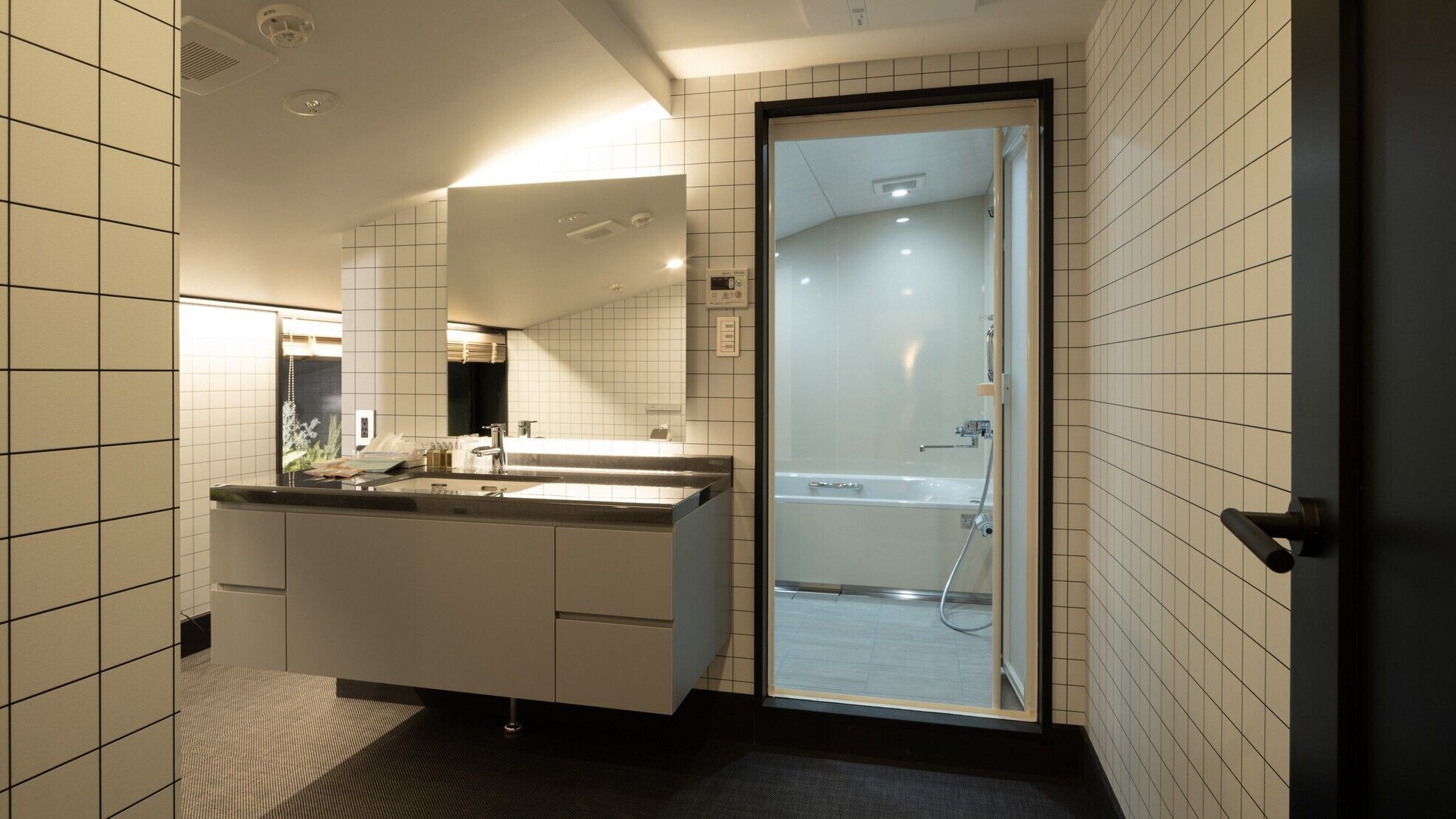 A modern bathroom with a large mirror, a sink, and a glass-enclosed shower.