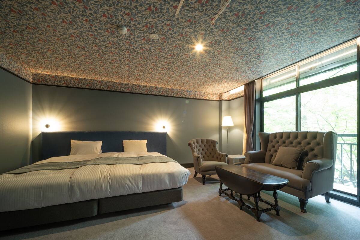 A bedroom with a large bed, a sofa, a chair, and a table.