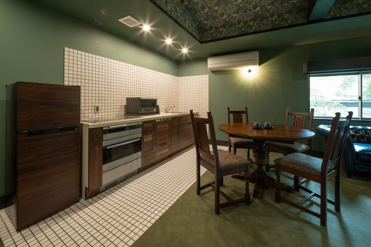 A kitchen with a dining area, featuring a tiled backsplash, wooden cabinets, and a round dining table with chairs.