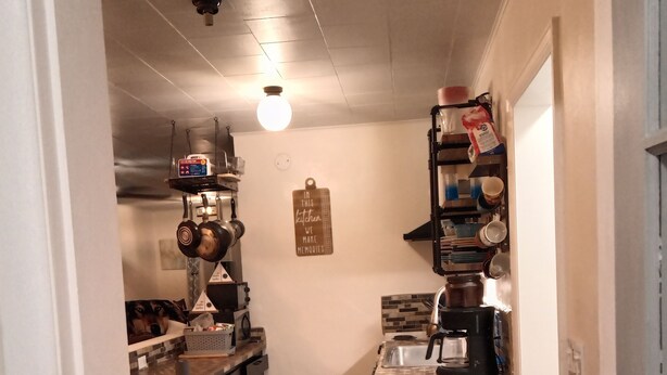 Eine Küche mit einer Kochinsel, einer Pendelhängung für Töpfe und einer Kaffeemaschine.
