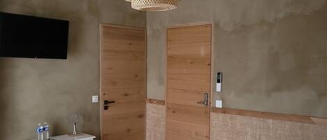 A bedroom with a bed, a dresser, a TV, and two wooden doors.