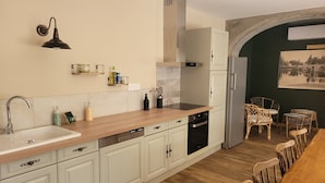 A kitchen with white cabinets, a wooden countertop, a sink, a stove, and a dining area with chairs.