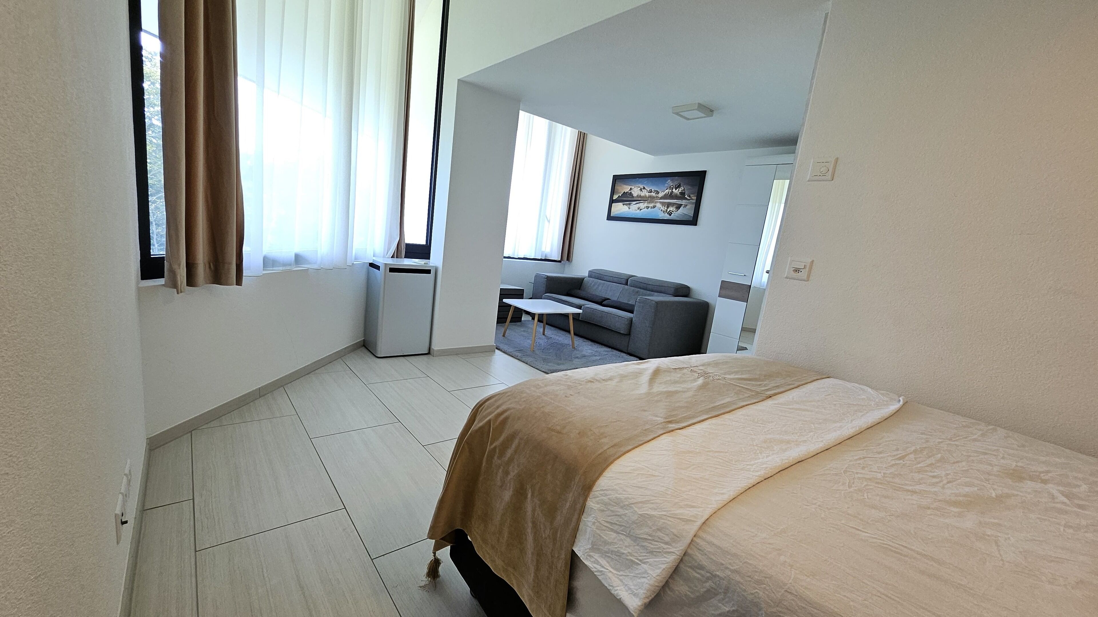 Una camera d'albergo con un letto, un tavolino, un divano e una finestra con tende.