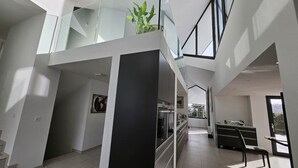 A spacious, modern interior with a high ceiling, a staircase leading to an upper level, and a dining area with a view of the outdoors. - Hilltop Luxury Villa with Minigolf, Indoor Pool, Wellness & Spa (Oberbütschel)