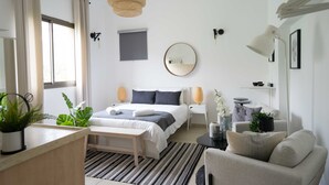A modern bedroom with a bed, bedside tables, a round mirror, and a bedside lamp. - YARKON - By Beach Apartments TLV (Tel Aviv)