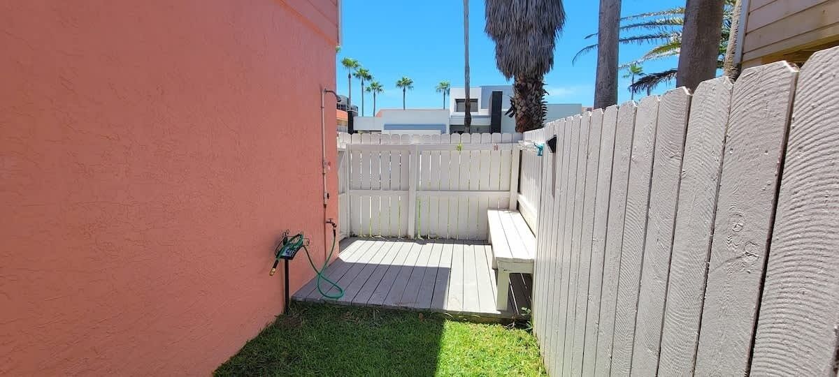 A fenced backyard with a wooden deck and a grassy area.