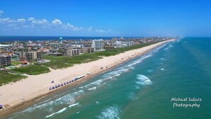 An aerial view of a coastal city with a long beach, buildings, and the ocean. - Casa Rosita 3 Bedroom Home by RedAwning (South Padre Island)