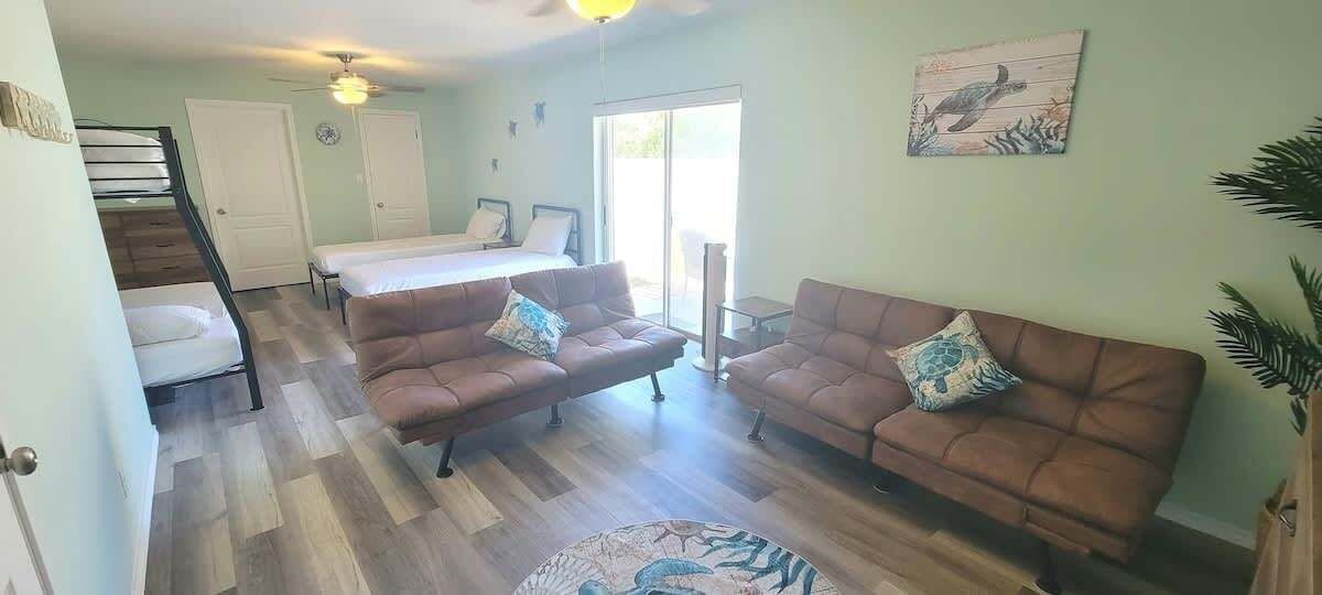 Ein geräumiger Wohnbereich mit zwei braunen Sofas, einem kleinen runden Teppich und einem Bett im Hintergrund.