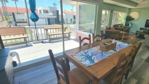 A spacious living area with a wooden dining table, comfortable seating, and a large TV. - Casa Rosita 3 Bedroom Home by RedAwning (South Padre Island)