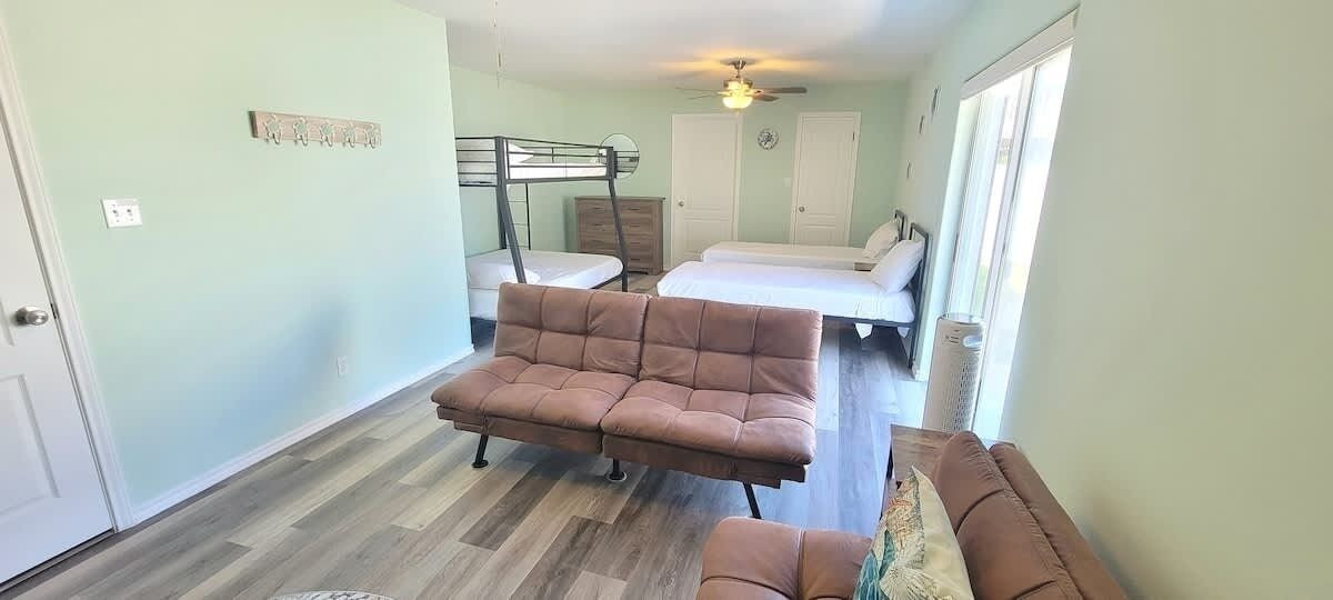 A room with a bunk bed, a sofa, and a bed.