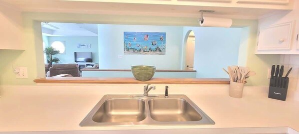A kitchen with a double sink, a green bowl, and a knife block.