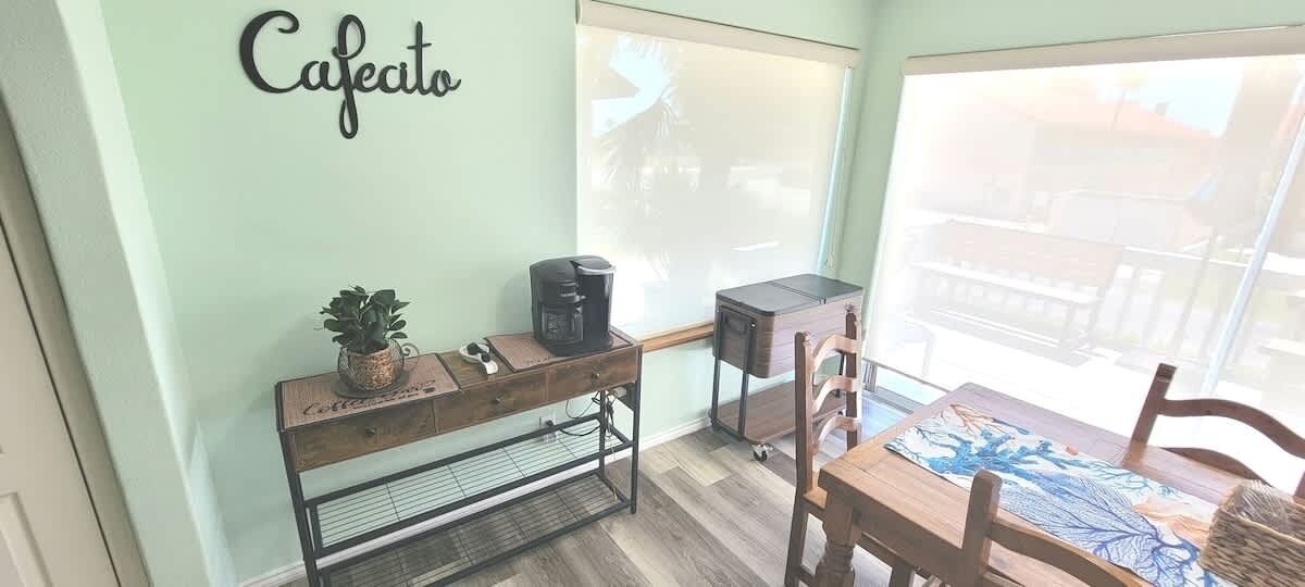 A cafe area with a coffee machine, a small plant, and a wooden table with chairs.