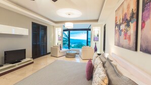 Ein modernes Wohnzimmer mit großem Fenster, Flachbildfernseher und einer gemütlichen Sitzecke.