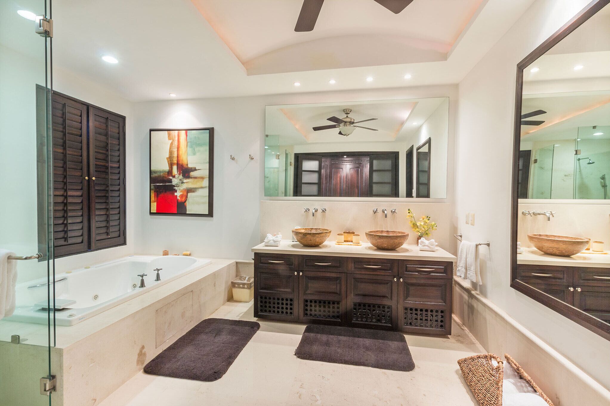 Une salle de bain moderne avec une grande baignoire, des meubles en bois foncé, un ventilateur de plafond et un grand miroir.