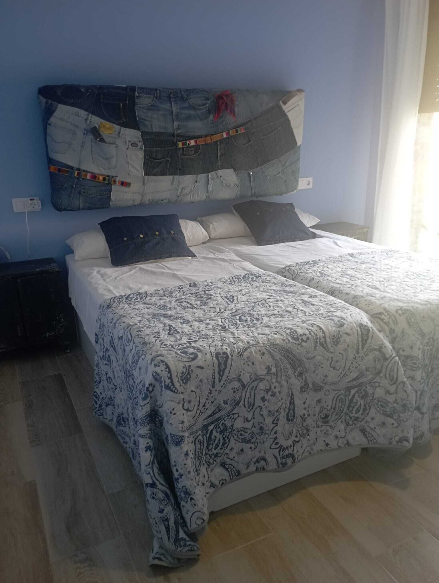 Ein Schlafzimmer mit zwei Betten, einer blauen Wand und einem Fenster mit Vorhängen.