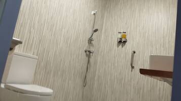 A bathroom with a toilet, a shower with a handheld showerhead, and a sink with a faucet.