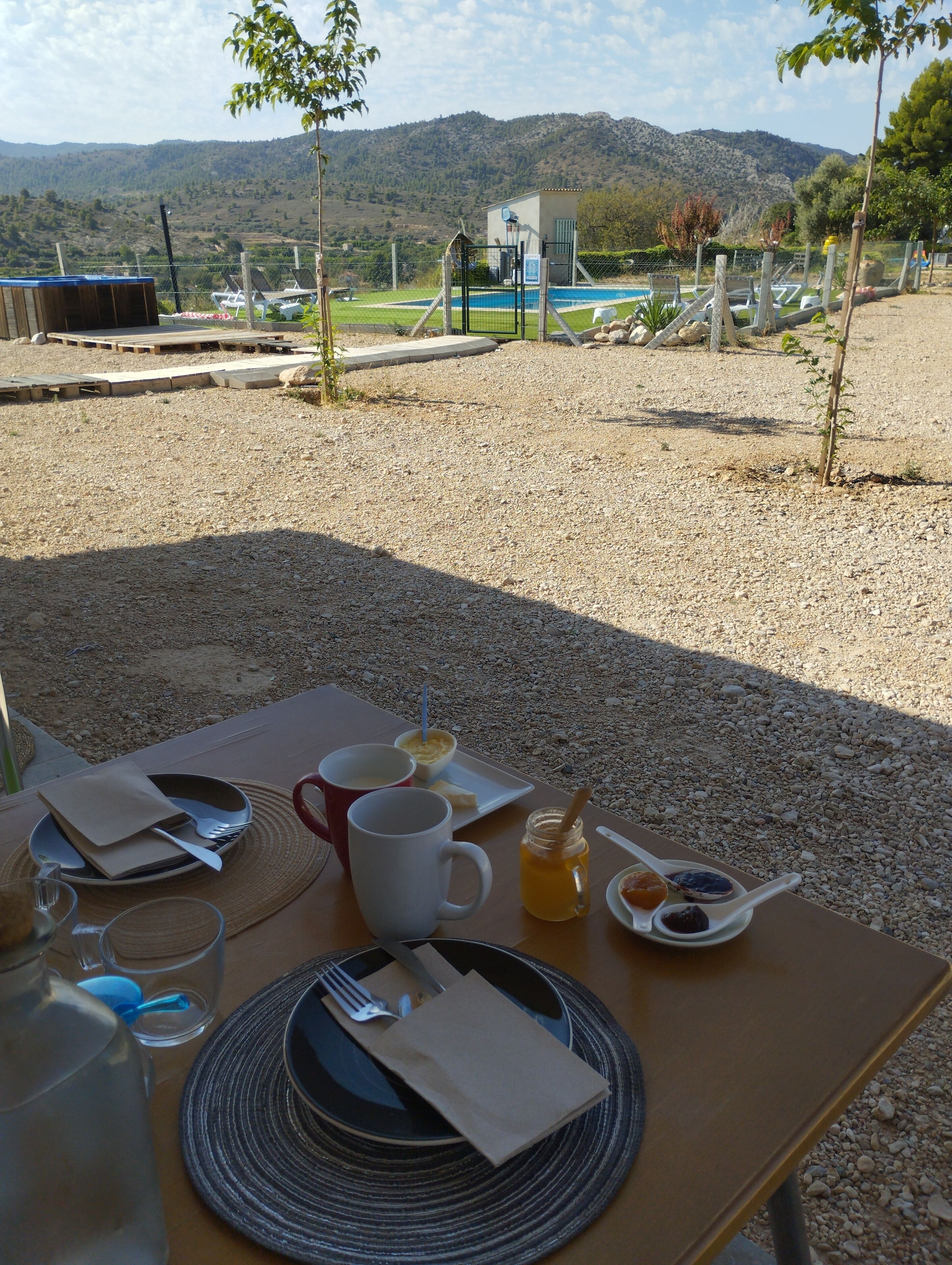 A table set outdoors with a view of a pool and mountains.