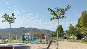Une table offrant une vue sur un paysage montagneux, un espace clos avec une piscine et un petit arbre.