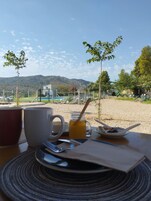 Una mesa con vistas a un paisaje montañoso, un área cercada con piscina y un pequeño árbol.