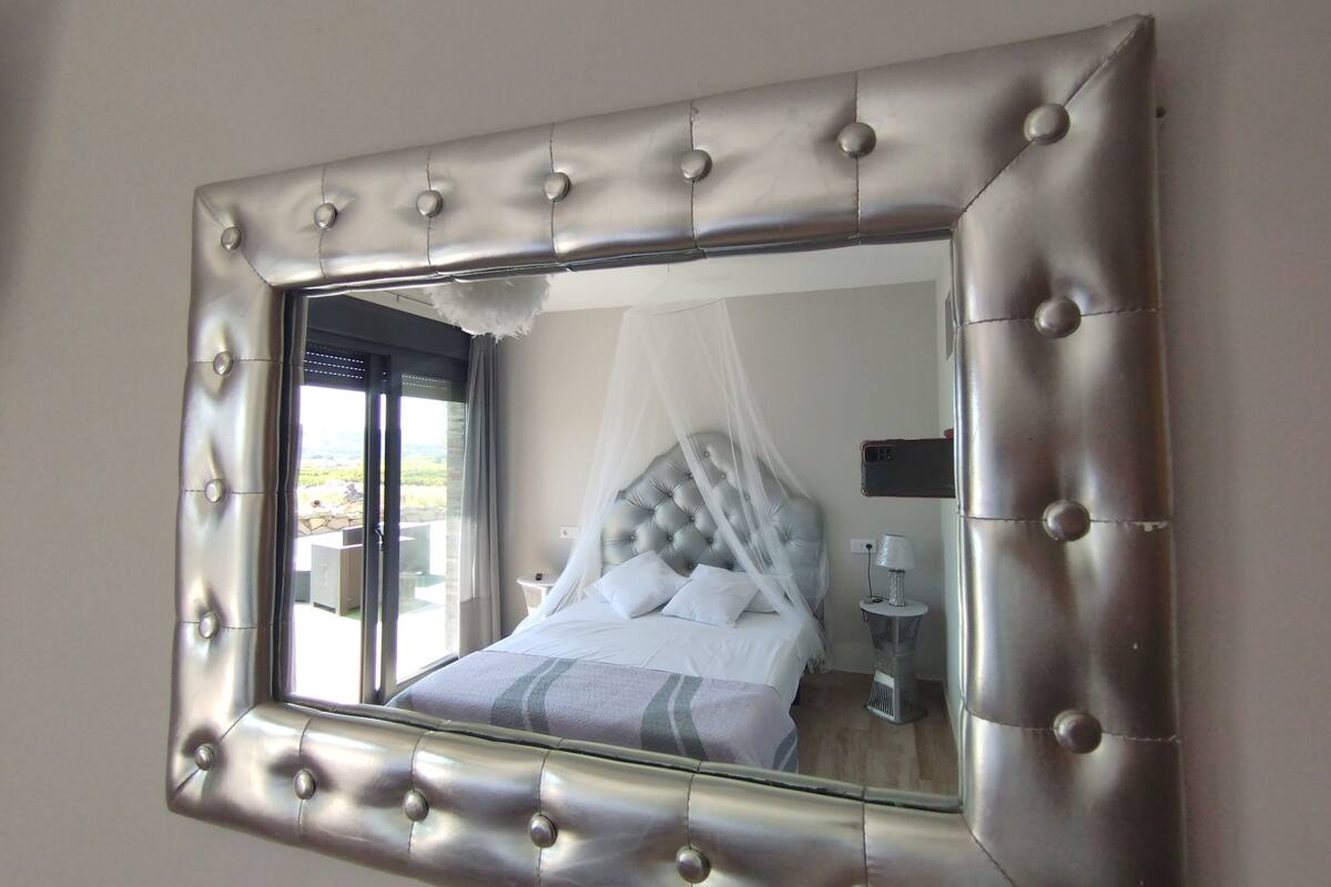 A bedroom with a tufted headboard, a bed with white bedding, a bedside table, and a nightstand.