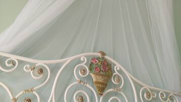 Een bed met een wit metalen frame en een hemelbed.