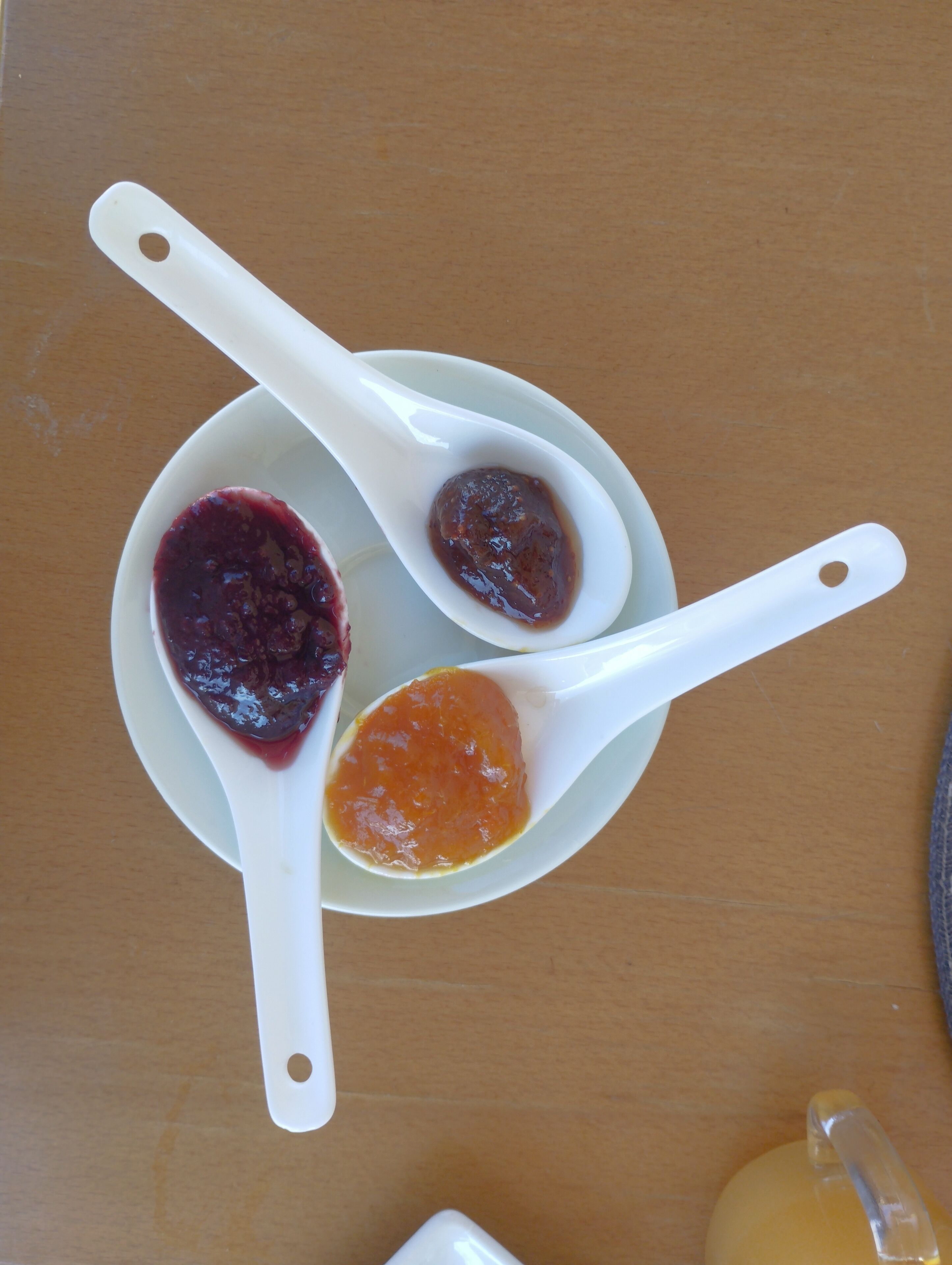 Three white spoons with different colored substances on a white plate.