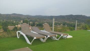 Una piscina al aire libre, sombrillas, sillones reclinables de piscina