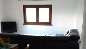Una sala de estar con un sofá, una televisión y un comedor con mesa y sillas.