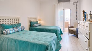 A bedroom with two beds, a dresser, and a chair. - Casa da Praia with pool area
 (Porches)