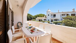 A balcony with a table and chairs, a stop sign, and a view of a white building with a dome and multiple windows. - Casa da Praia with pool area
 (Porches)