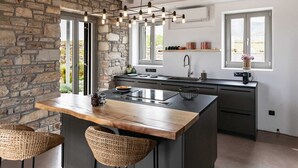 Een moderne keuken met een groot eiland, stenen muren en uitzicht op de omgeving.