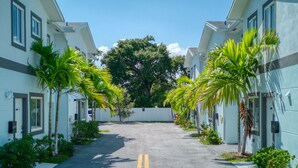 A residential street with two-story houses, a clear sky, and a central road with a double yellow line.