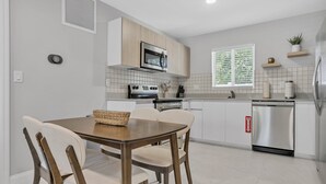 A modern kitchen with a dining table, chairs, and built-in appliances.