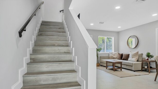 A staircase with wooden steps and white walls, leading to a living area with a sofa and a coffee table.